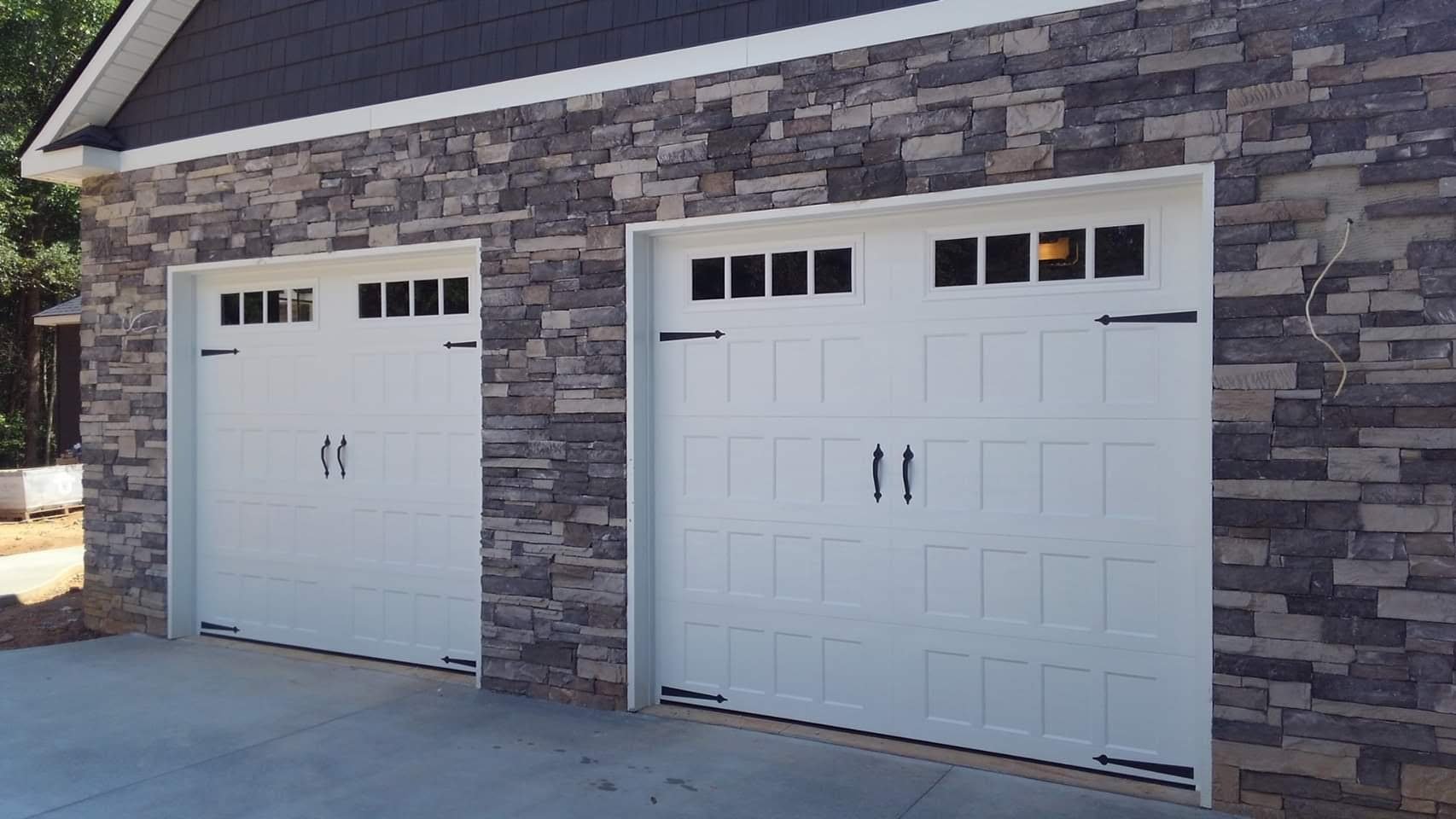 White carriage-house garage doors on a stone front home