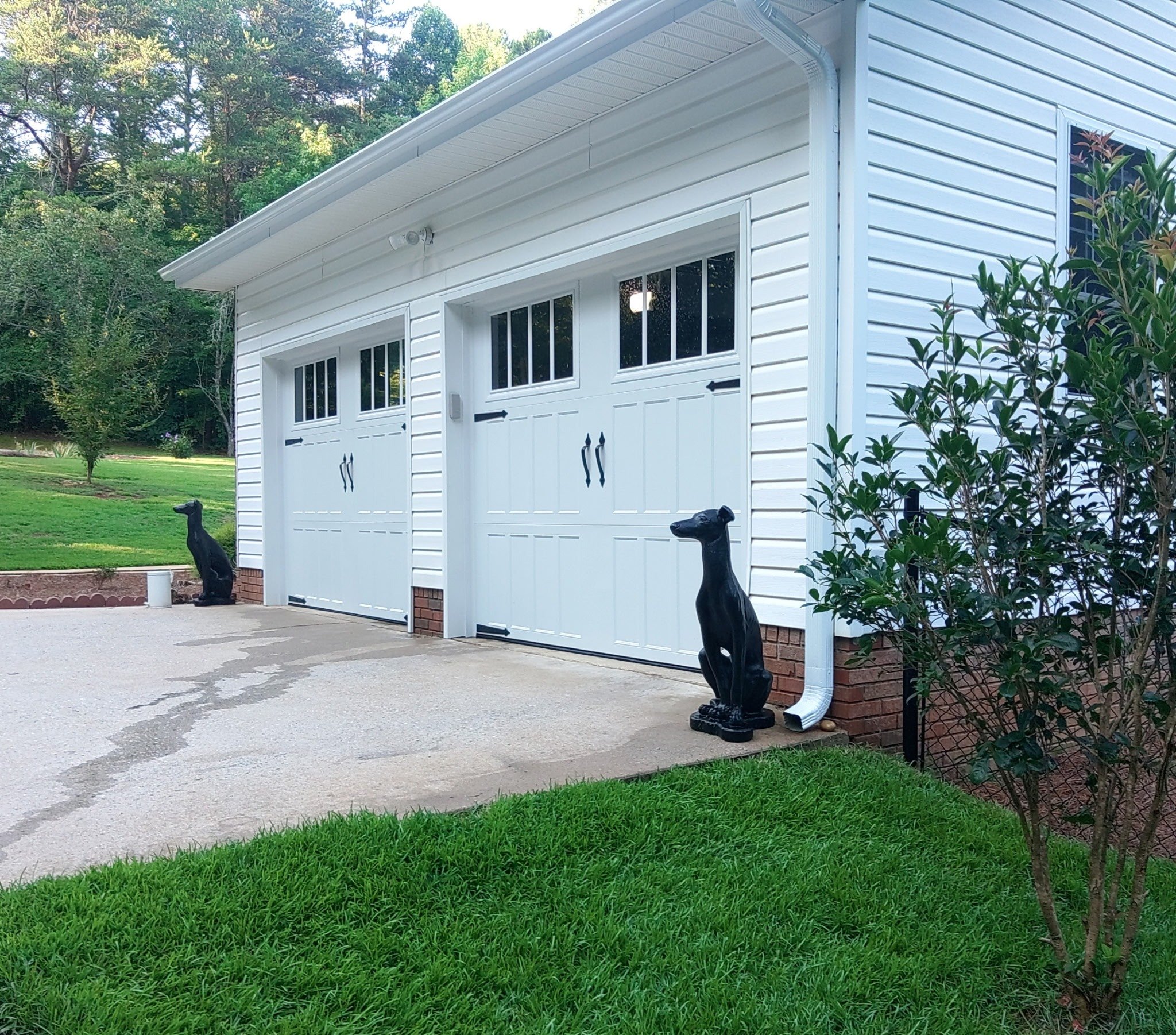 White garage doors with landscaping and driveway